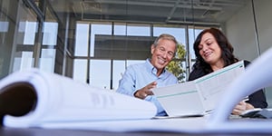 Smiling man and woman reviewing documents at a table.