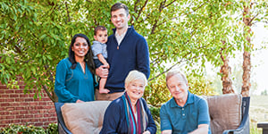 Multiple generation family enjoying day outdoors smiling at camera.