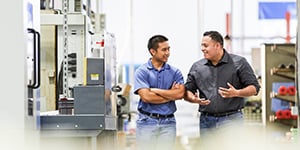 Two men having a conversation as they walk through a manufacturing facility.