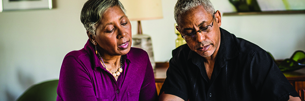 A man and woman sitting at a table looking at a document.