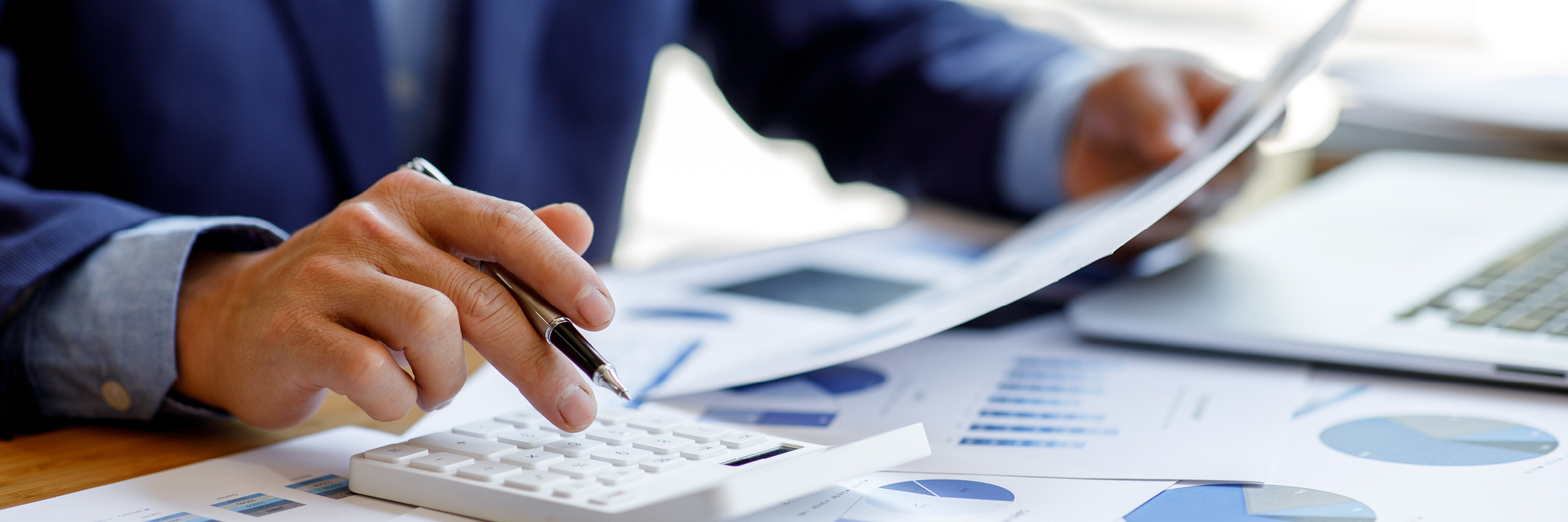 A man's hands are seen as he looks at papers and his calculator.