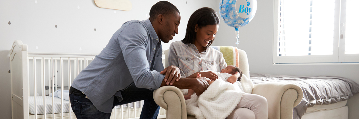 A man and a woman are in a nursery with the woman holds a baby in her lap.