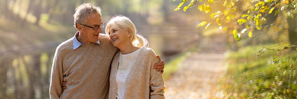 A mature man and woman walk on a trail.