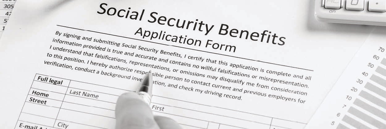 Fingers can be seen holding a pen over a Social Security application