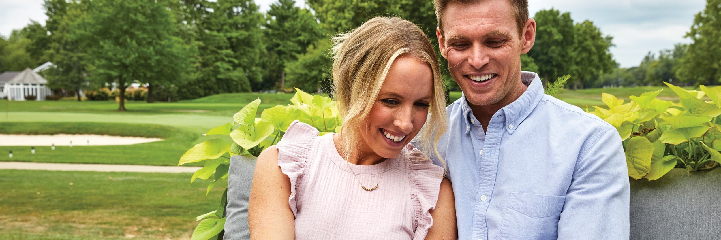 A man and woman smile as they look at their phone.