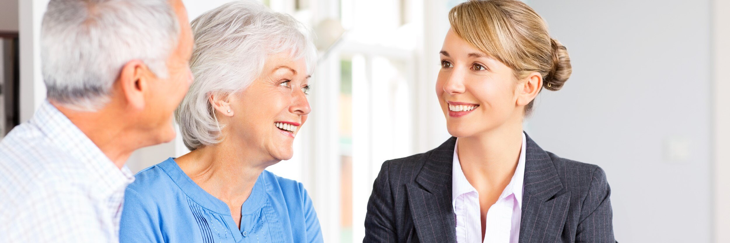 An older man and woman talk to a younger woman.