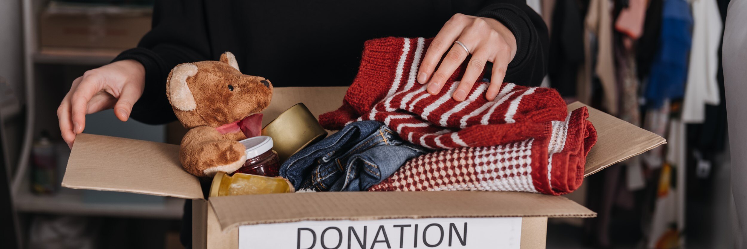 A woman stands behind a box of toy donations with a 'donations' note on the box.