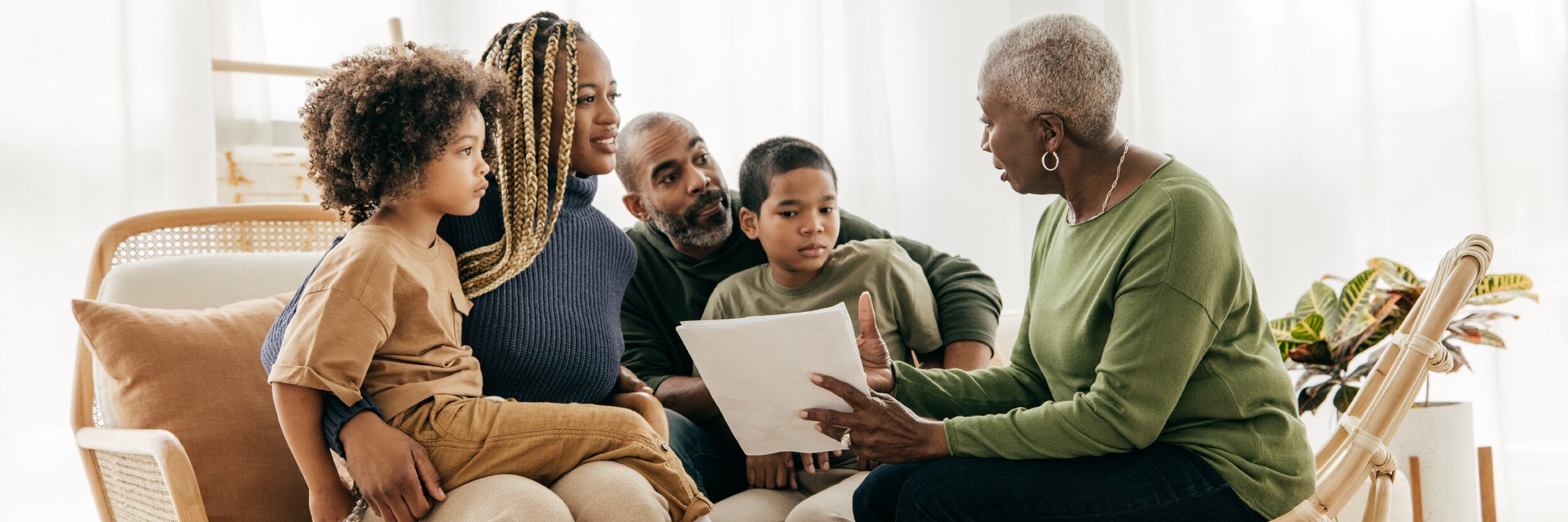 An older woman holds paperwork while sitting down with a younger woman and man and two boys.