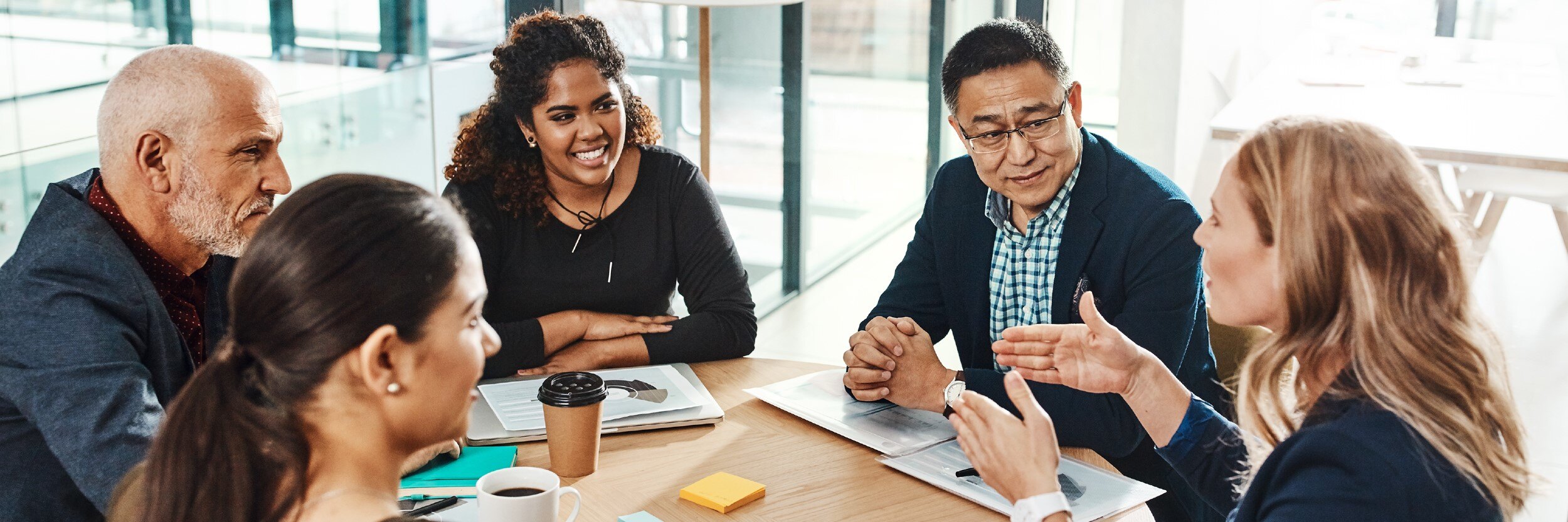 A group of individuals sit around a table during a meeting.