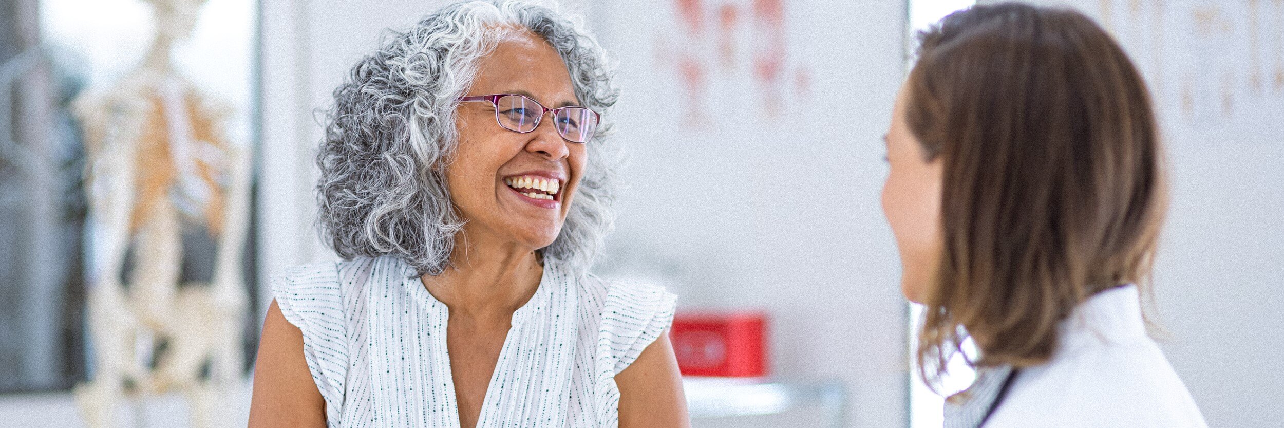 A woman smiles as she talks with a doctor.