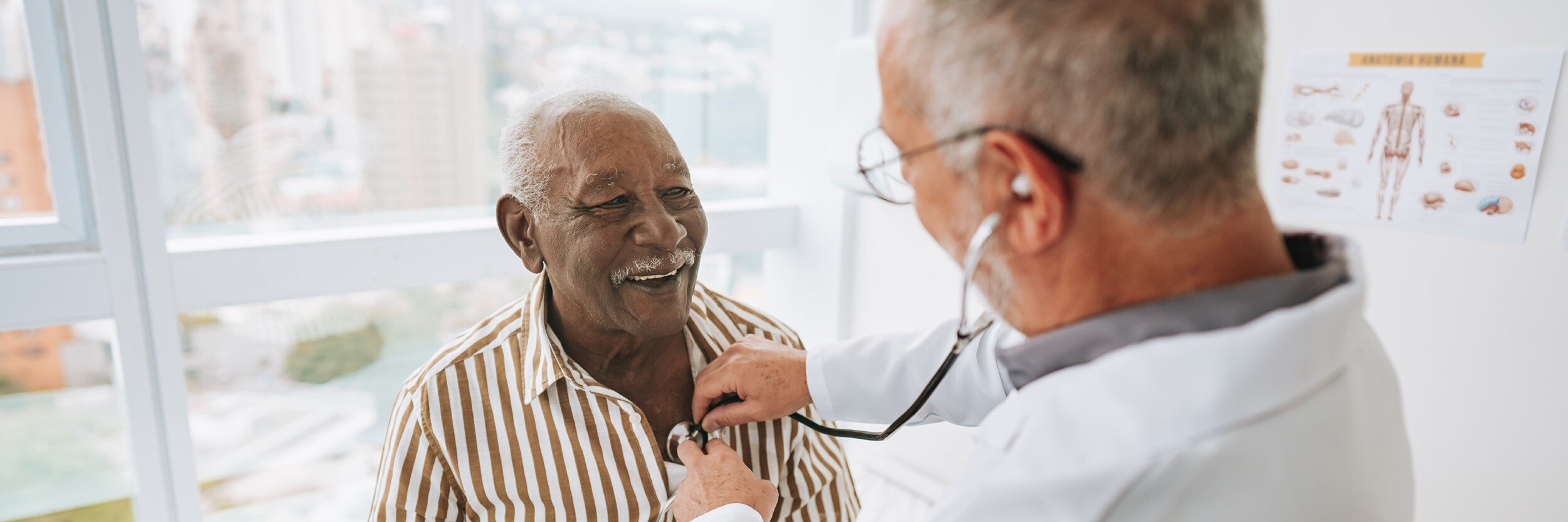 A doctor listens to an older man's heart with a stethoscope.