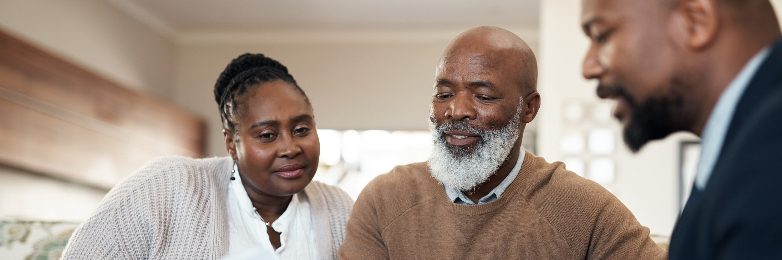 A man and woman sit with another man looking at papework