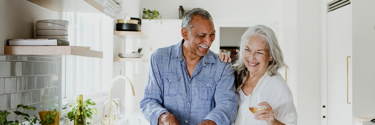 A man and woman stand in a kitchen counter.