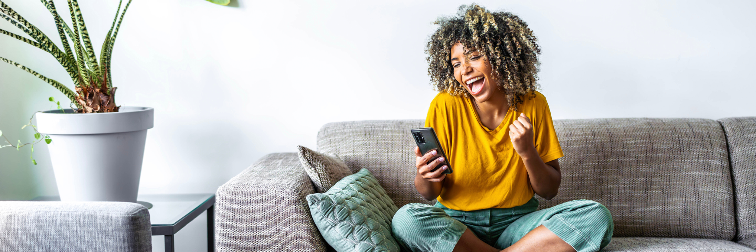 A woman sits on a couch, looking at her phone.