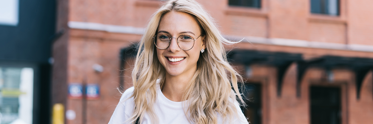 A woman with glasses standing on the street.