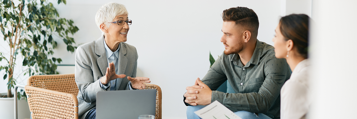 A man and woman talk to an older woman while sitting down.