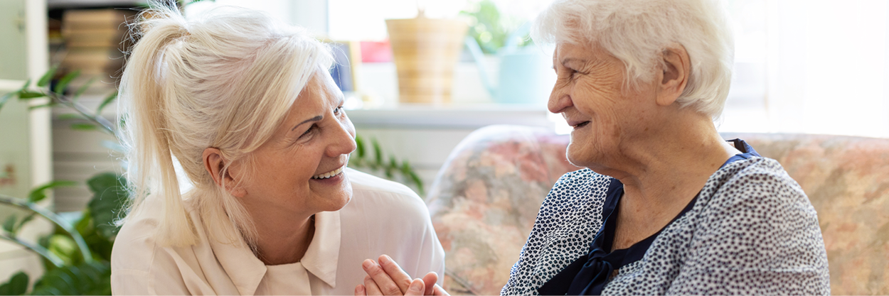 Two mature women sit on a couch.