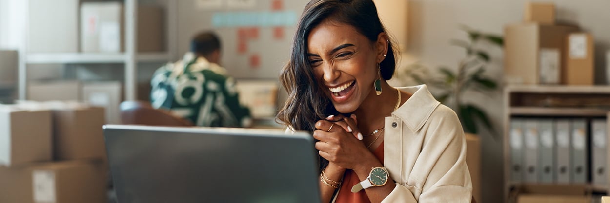 A woman sits looking at a laptop.