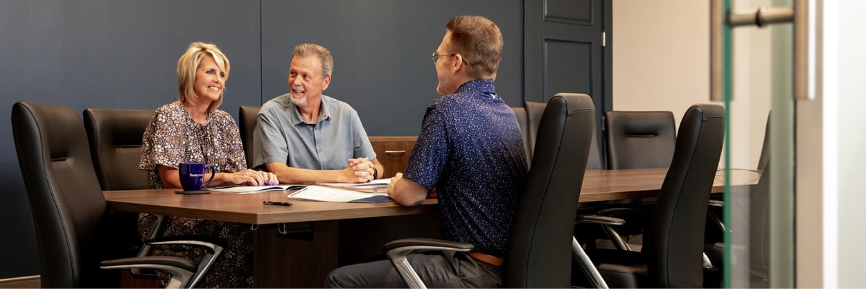 A man and woman sit at a conference table with another man.