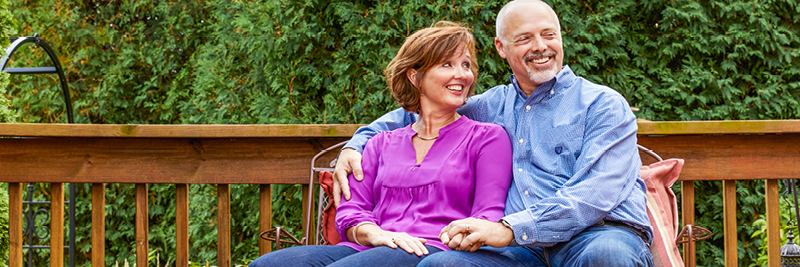 A man and a woman sit on a park bench, holding hands.