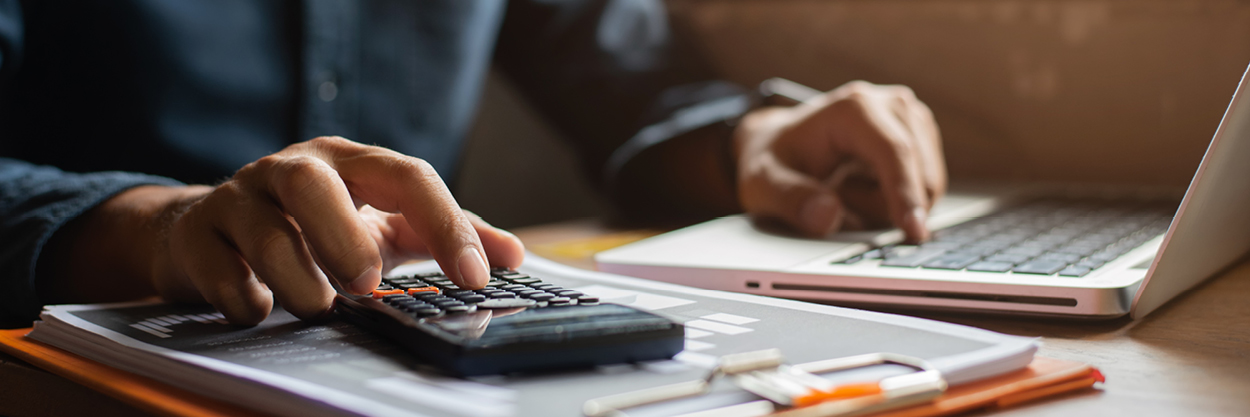 A man's hand is shown as he uses a calculator