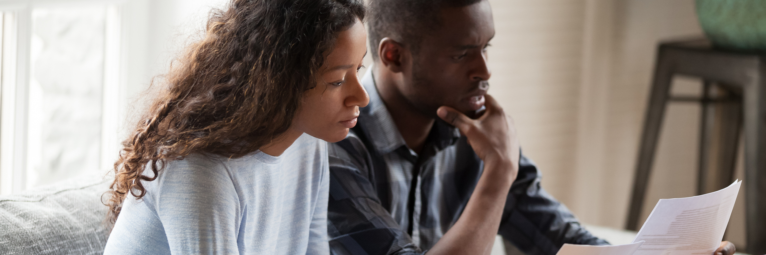 A man and woman are sitting down, looking at some papers.