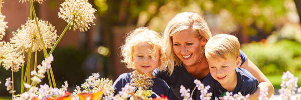 A woman and two small children look at flowers.