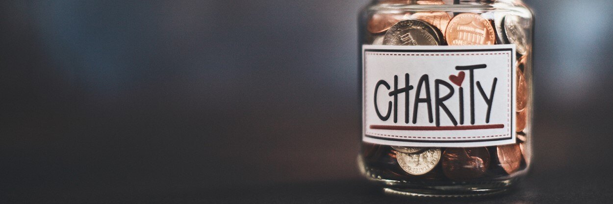 A jar filled with change that has a "charity" sticker on it.