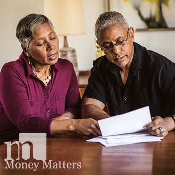 A man and woman sit at a table reviewing some paperwork.