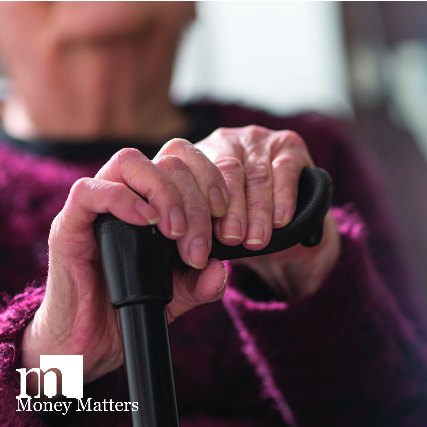 An elderly woman's hands rest on a black cane