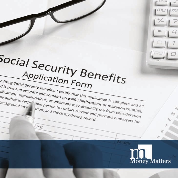 Fingers can be seen holding a pen over a Social Security application