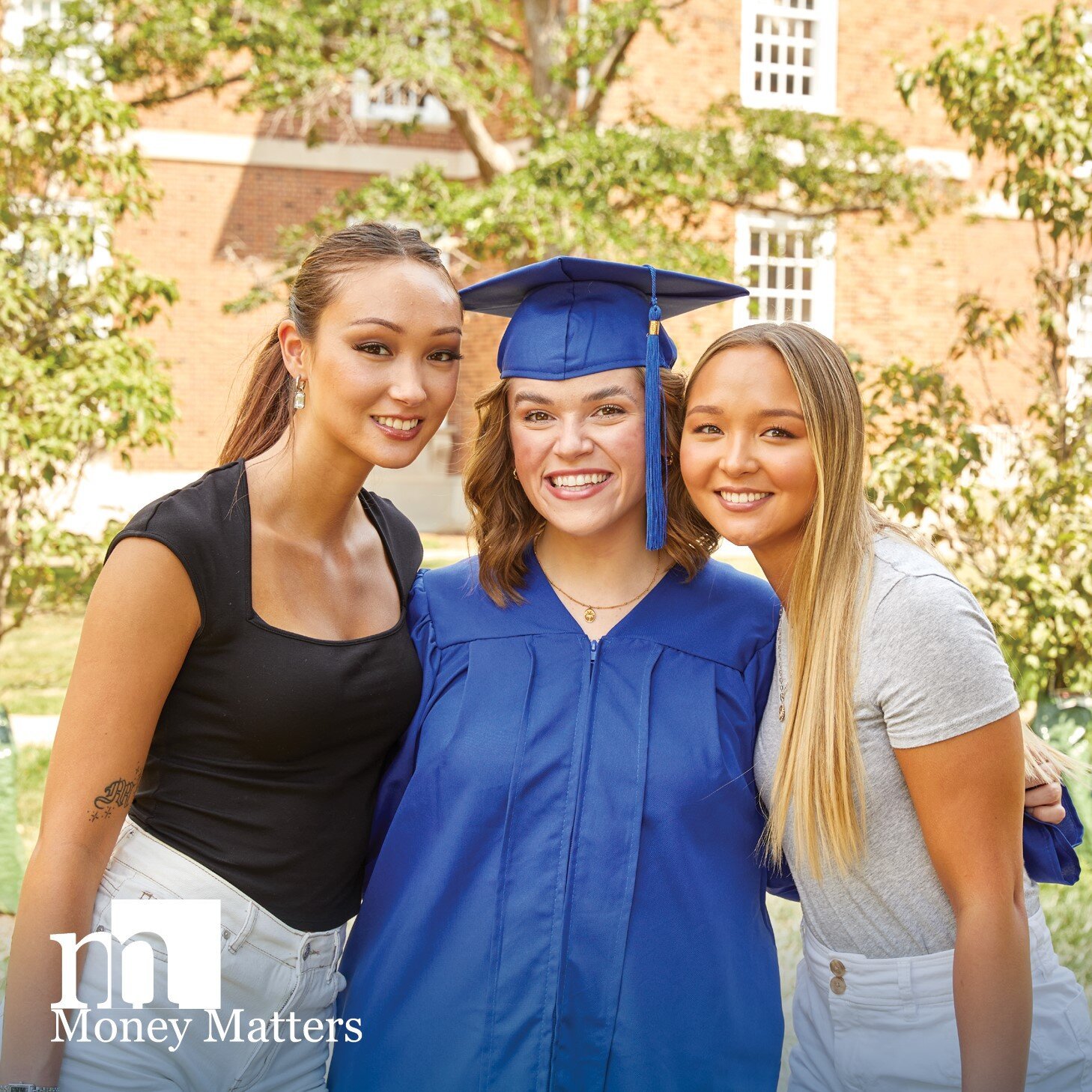 Two women pose with another woman wearing a graduation cap and gown.