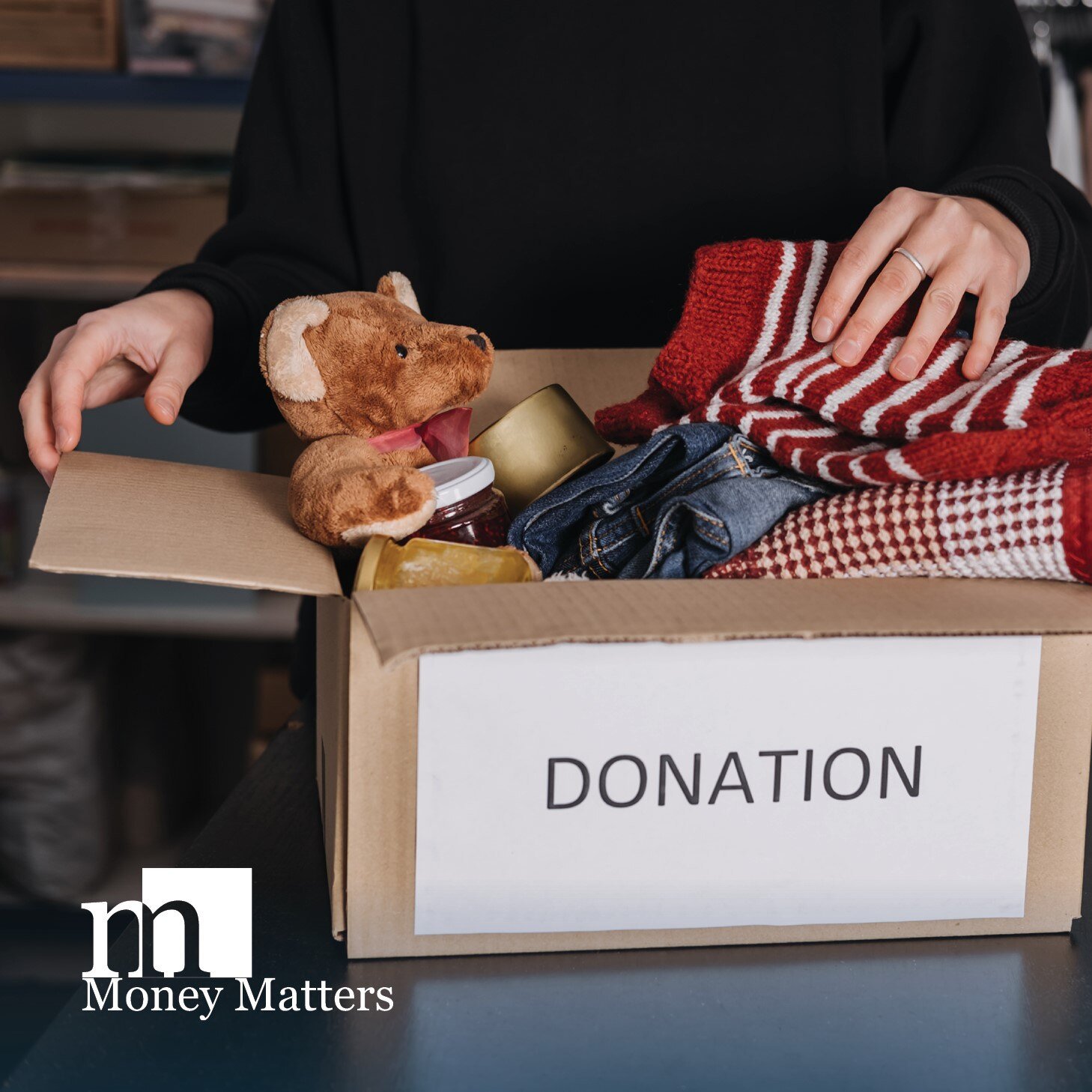 A woman stands behind a box of toy donations with a 'donations' note on the box.