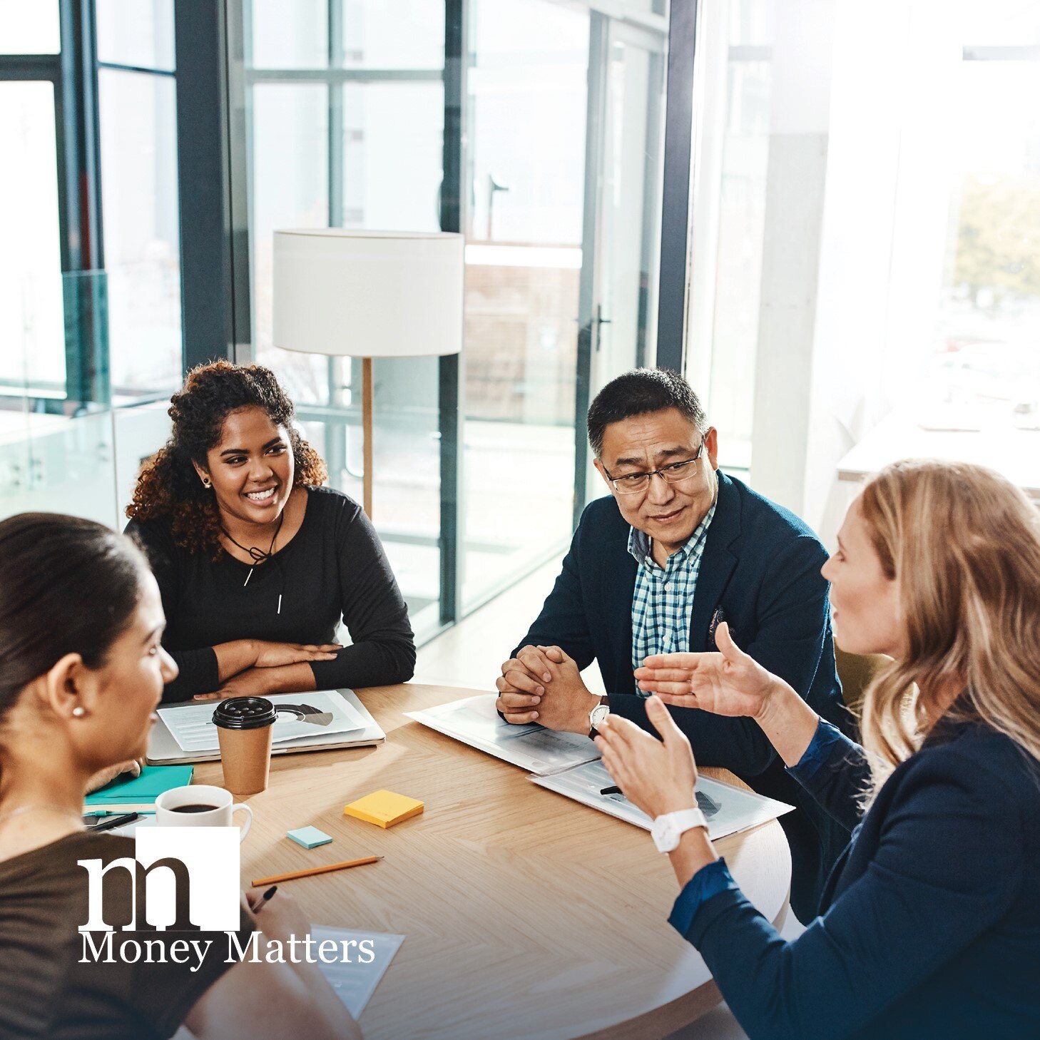 A group of individuals sit around a table during a meeting.