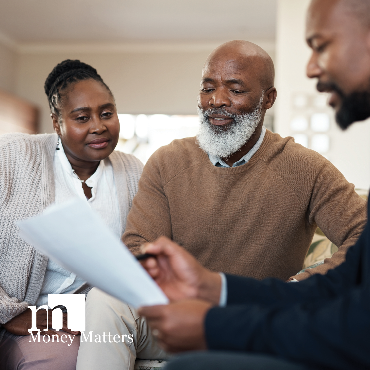 A man and woman sit with another man looking at paperwork