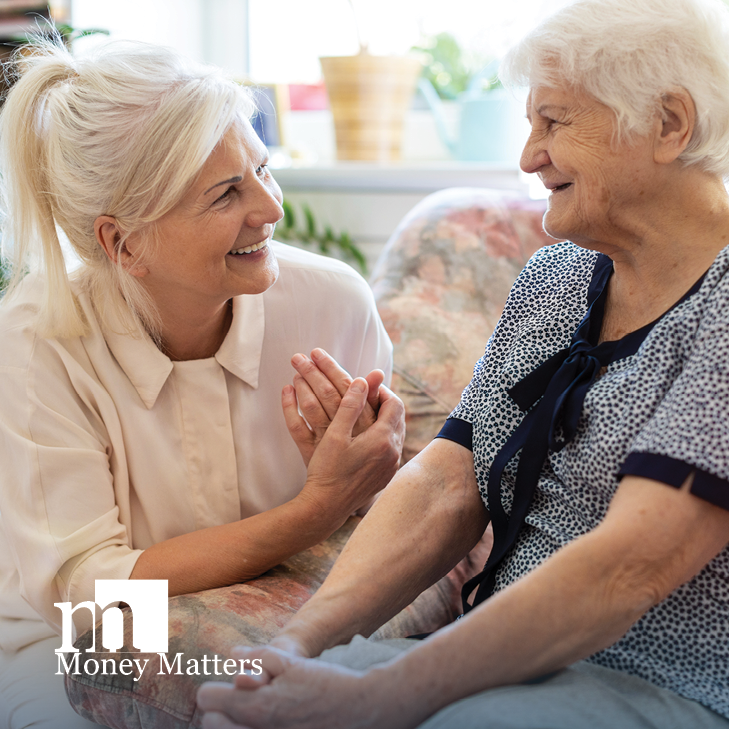 Two mature women sit on a couch.