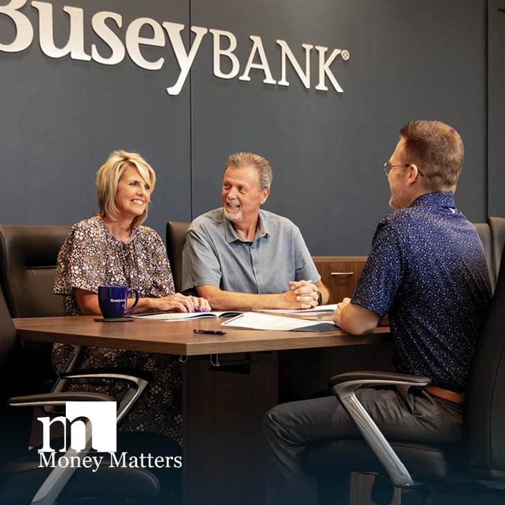 A man and woman sit at a conference table with another man.