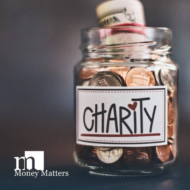 A jar filled with change that has a "charity" sticker on it.